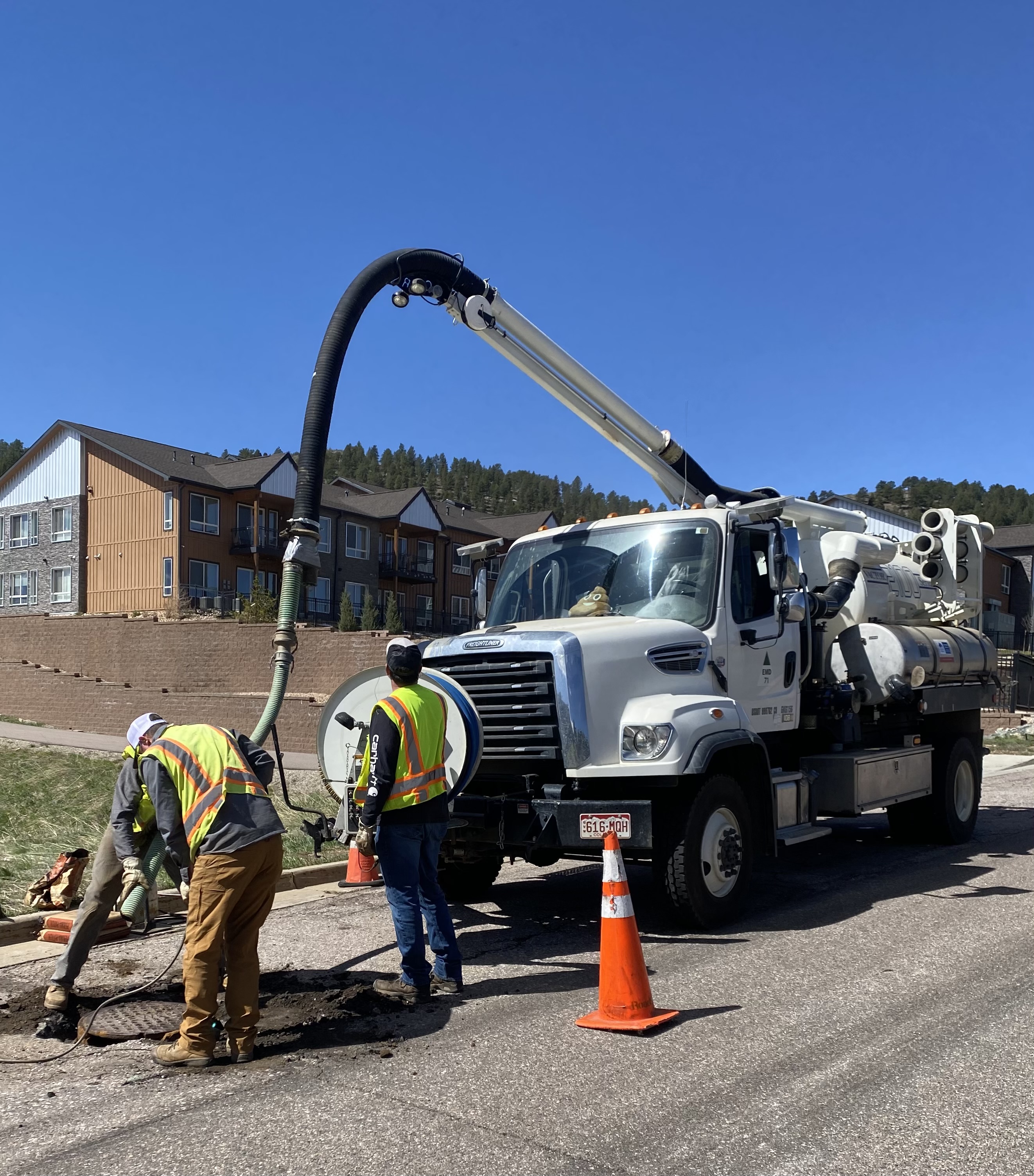 Picture of C&D employees in front of a jetting truck. They are jetting out the sewer main.